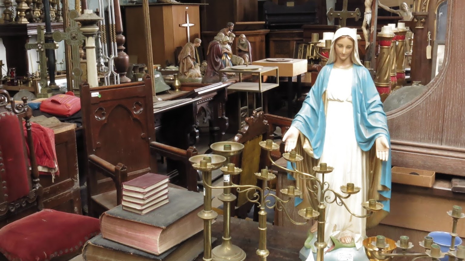 Church antiques in our Betchworth showroom — brass candlesticks, chapel chairs, statuary and carved oak furniture