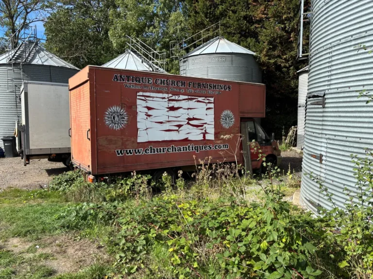The old Antique Church Furnishings lorry, painted with the company name and website, parked beside the farm grain silos