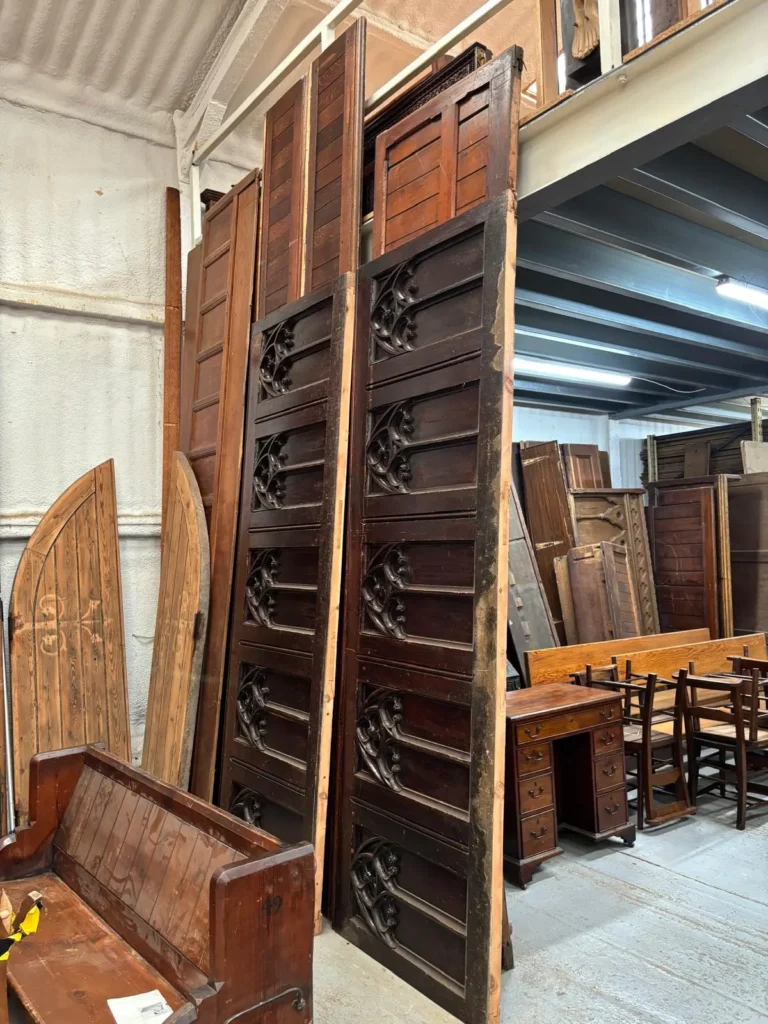 Tall carved oak church panels and doors standing along the warehouse wall